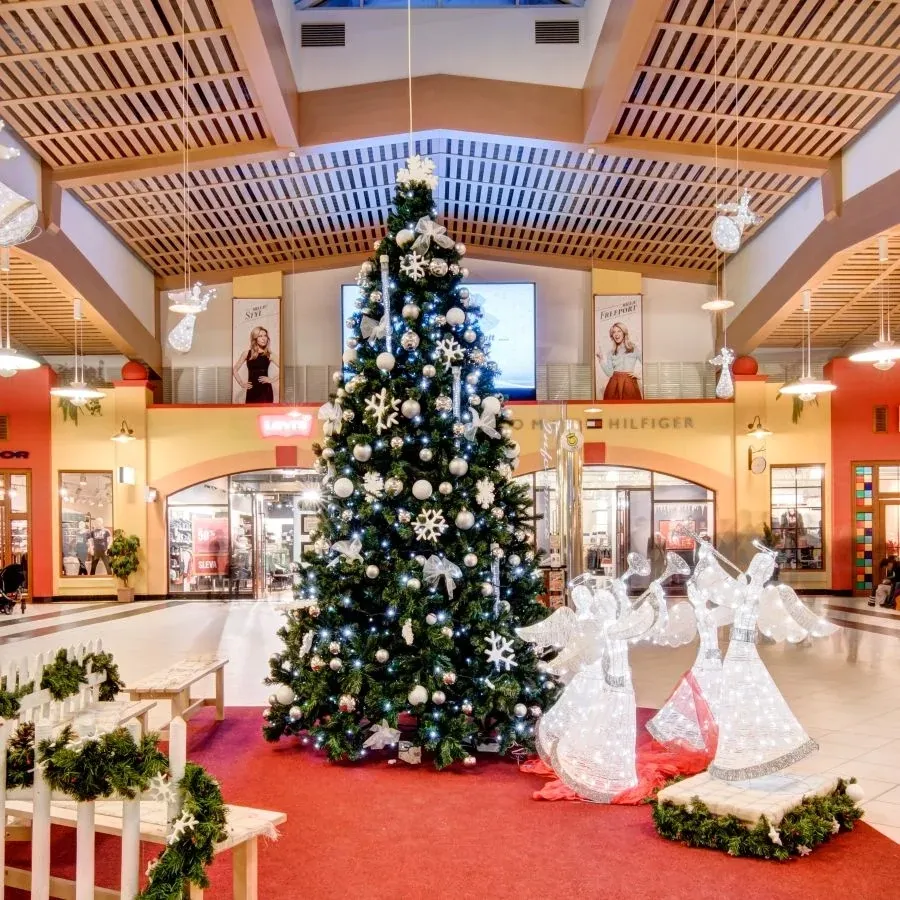 Eisweiße Lichtengel mit Trompete an einem Weihnachtsbaum in der Passage eines Einkaufszentrums, Fotoecke